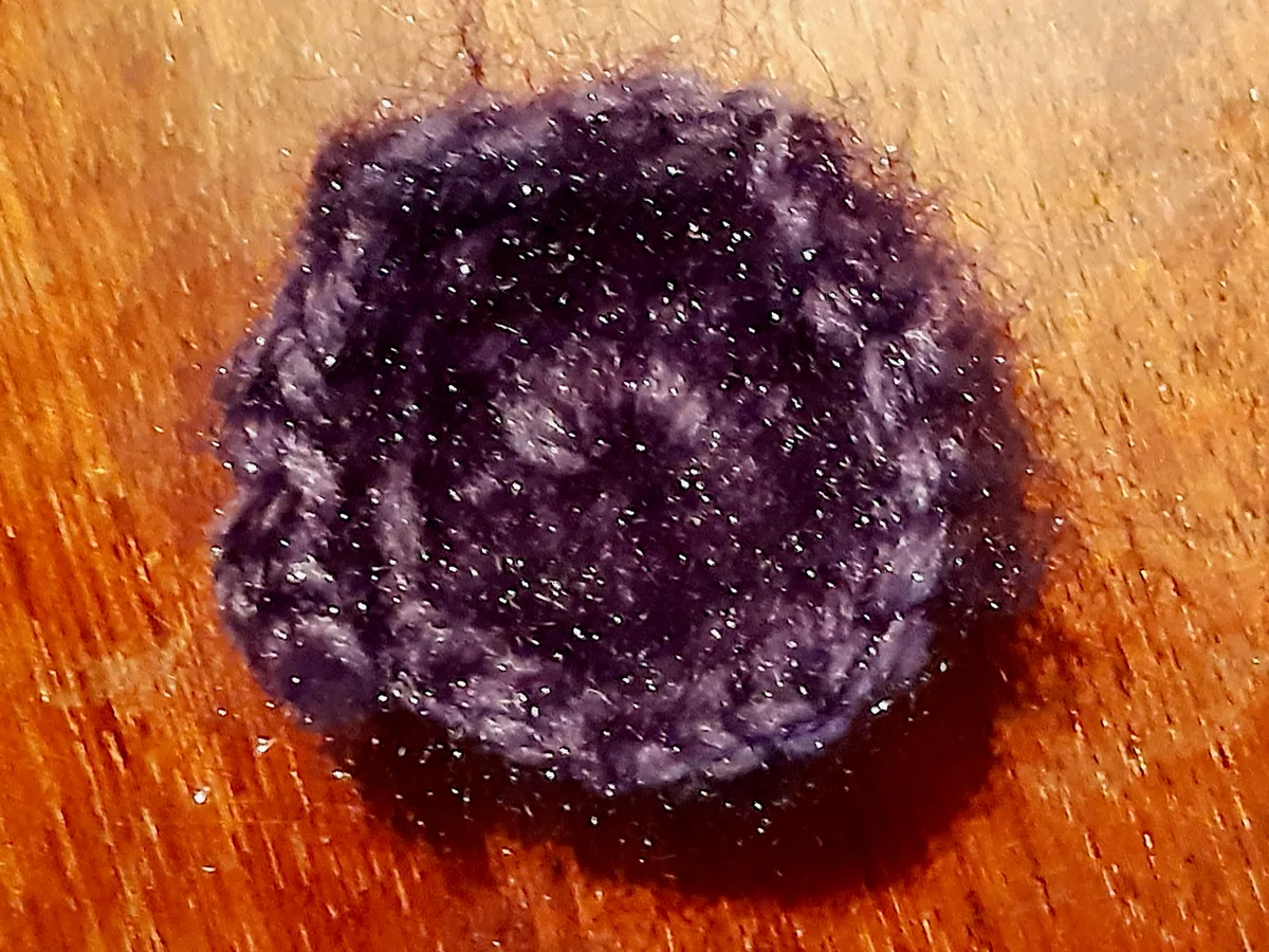 The edge of a real purple crochet motif, for comparing regular motifs with freeform work; not the artist’s work.